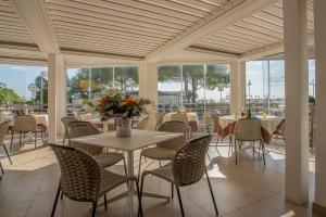 a dining room with tables and chairs and windows at Hotel Sirenetta in Grado