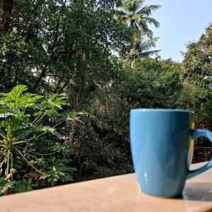 a blue coffee cup sitting on top of a table at Palolem by Casa de Palmora in Canacona +7 photos