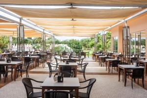 an empty restaurant with tables and chairs at Hotel Mariant Park in Sa Coma