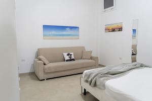 ein Wohnzimmer mit einer Couch und einem Bett in der Unterkunft Stelle Gemelle Residence by ThePuglia in Torre Lapillo