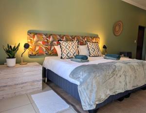 een slaapkamer met een groot bed met kussens erop bij New Wave Village in George +2 foto's