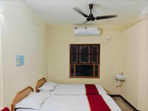 a bedroom with two beds and a ceiling fan at Daya Dharmam Residency in Tiruvannāmalai