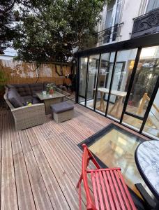 eine Terrasse mit einem Sofa und einem Tisch und Stühlen in der Unterkunft Superbe appartement sur jardin- proche de paris in Vanves + 3 Fotos