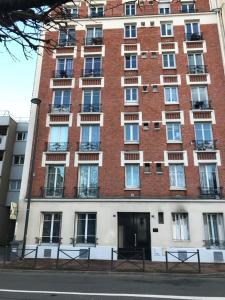 ein großes Backsteingebäude mit Fenstern auf einer Straße in der Unterkunft Superbe appartement sur jardin- proche de paris in Vanves