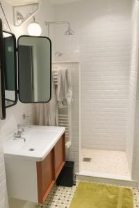 ein Badezimmer mit Waschbecken, Spiegel und Badewanne in der Unterkunft Superbe appartement sur jardin- proche de paris in Vanves