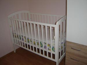 a white crib in a room next to a dresser at Gemütliches Appartment Direkt Am Strand in Koromačno