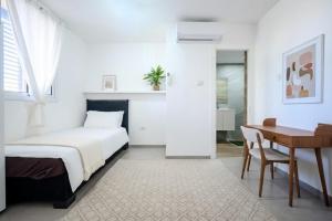 a white bedroom with a bed and a desk at Ashdod 5 rooms with mamad in Ashdod