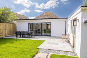 a white house with a patio and grass at Seaside Bungalow with Garden & Inflatable Hot Tub in Hamworthy