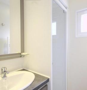 a white bathroom with a sink and a mirror at TI WAR AN DOUR in Guégon