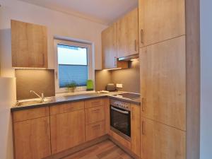 a kitchen with wooden cabinets and a window at Apartment in Piesendorf near Ski Slopes in Piesendorf +18 photos