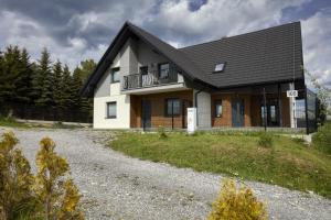 Zubrzyca DolnaCozy mountain house - Coolówka pod Babią Górą的白色的房子,有黑色的屋顶和碎石车道
