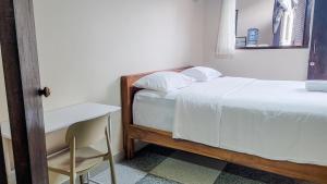 a bedroom with a bed and a desk and a chair at Capung Guesthouse in Jimbaran