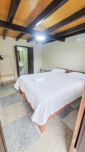 a bedroom with a large white bed in a room at Capung Guesthouse in Jimbaran