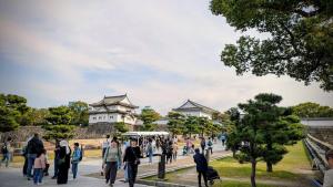 Un gruppo di persone che camminano davanti a un castello. di O's Apartment Hotel In Kyobashi 3FB ad Osaka