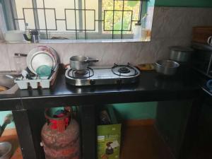 a kitchen counter with a stove and some pots and pans at Noah Yourt in Siolim