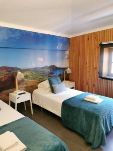 a bedroom with two beds and a painting on the wall at Globo Happy Hostel in Angra do Heroísmo