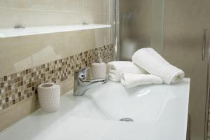 ein Bad mit einem Waschbecken, Handtüchern und einem Wasserhahn in der Unterkunft Stelle Gemelle Residence by ThePuglia in Torre Lapillo + 56 Fotos