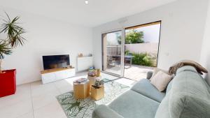 ein Wohnzimmer mit einem blauen Sofa und einem Fernseher in der Unterkunft Casa 3 Merlyne Plage in Saint-Gilles-Croix-de-Vie