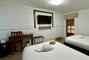 a bedroom with two beds and a desk and a television at Baan inta hostel - บ้านอินตาโฮสเทล in Phra Nakhon Si Ayutthaya