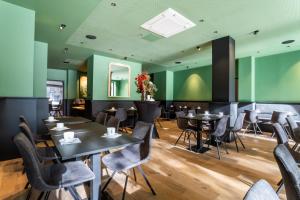 a restaurant with black tables and chairs and green walls at Brueghel in Lille
