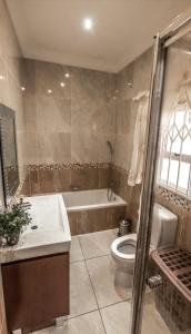 a bathroom with a tub and a toilet and a sink at Ekupholeni Garden Villas in Manzini