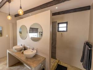 a bathroom with two sinks and two mirrors at Nauams Namibia - Farmyard Chalets, Mountain Cabins and Campsite in Namibgrens +64 photos