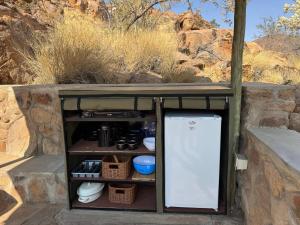 a small refrigerator with a door in a stone wall at Nauams Namibia - Farmyard Chalets, Mountain Cabins and Campsite in Namibgrens