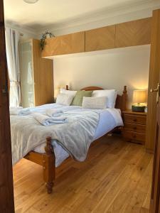 ein Schlafzimmer mit einem großen Bett mit Holzboden in der Unterkunft Cysgod Bach & Caban y Saer Cottages in Bala