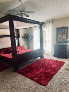 - une chambre avec un lit à baldaquin et un tapis rouge dans l'établissement Peaceful Oasis In Stonecrest, à Fairington