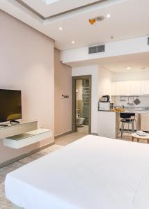 a living room with a white bed and a kitchen at Sedra Residence in Kuwait