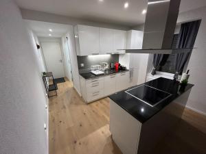 une cuisine avec des armoires blanches et un comptoir noir dans l'établissement Jasminkas Host 3 - Stadtwohnung mit Küche & gratis Parkplatz, à Saint-Gall