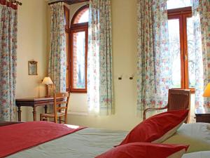 Un dormitorio con cama, escritorio y ventanas en Gîte lumineux avec jardin, draps inclus, près de Vichy - FR-1-489-281, en Trézelles