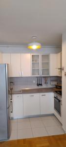 a white kitchen with white cabinets and a light at Lux Apartmans in Zagreb