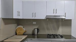 a kitchen with white cabinets and a stove top oven at Cosy Homes in Suva - 2BR Family Unit in Suva