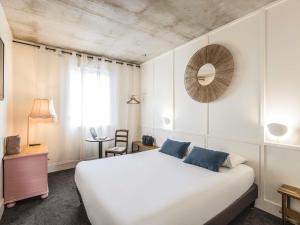 Un dormitorio con una gran cama blanca y un espejo. en Greet Hotel Limoges Nord, en Limoges