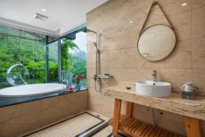 een badkamer met een bad, een wastafel en een spiegel bij Karst Scenic Hotel in Gaotian +97 foto's