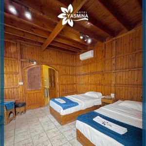 two beds in a room with wooden walls at yasmina hotel in Dahab