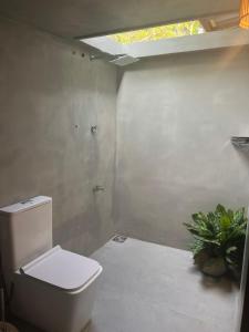 a bathroom with a white toilet and a plant at The Drop In Surfhouse Madiha in Madihe East