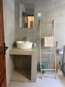 a bathroom with a sink and a towel ladder at The Drop In Surfhouse Madiha in Madihe East