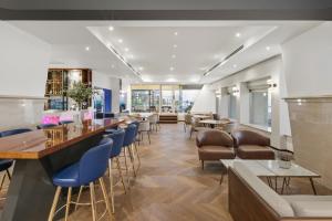 a restaurant with a bar with blue chairs and tables at Renaissance Tel Aviv Hotel in Tel Aviv