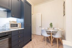 a kitchen with a table with chairs and a microwave at Battersea Boutique Apartments in Bangor