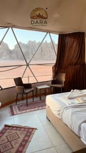 a bedroom with a bed and two chairs and a window at DARA RUM lUXURY CAMP in Wadi Rum