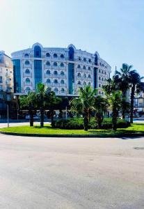 a large building with palm trees in front of it at can palace adalya otel in Antalya