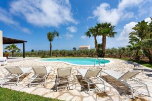 een groep stoelen rond een zwembad bij Villa delle Stelle in Scopello