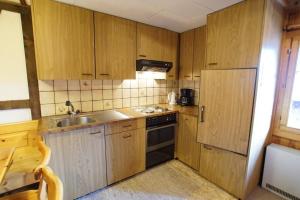 a kitchen with wooden cabinets and a sink and a refrigerator at Fewo Mit Blick Auf Die Berge in Sedrun