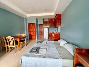 een slaapkamer met een bed en een tafel en een keuken bij Orient Hotel in Jomtien Beach