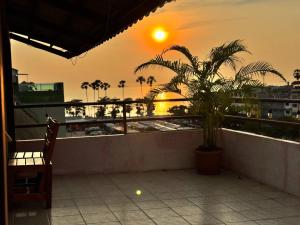 a view of the sunset from a balcony with a palm tree at Orient Hotel in Jomtien Beach