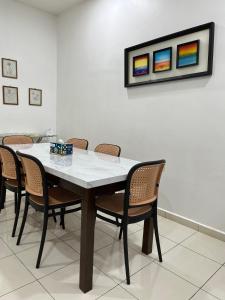 a dining room table with chairs and a painting on the wall at Magnolia 3 Homestay in Kampung Raja