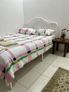 a bed with a striped blanket and a table at Magnolia 3 Homestay in Kampung Raja