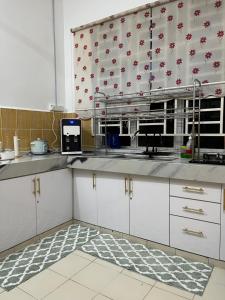 a kitchen with white cabinets and red and white wallpaper at Magnolia 3 Homestay in Kampung Raja